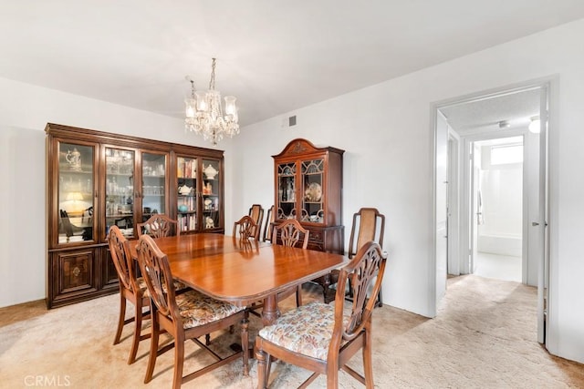 dining area with visible vents, light colored carpet, and an inviting chandelier
