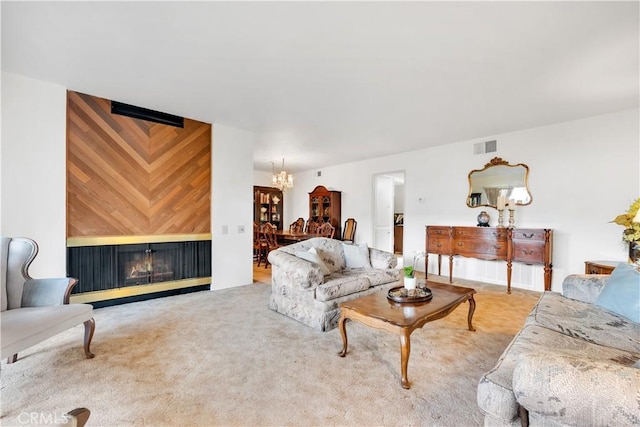 carpeted living room with a warm lit fireplace, visible vents, and a notable chandelier