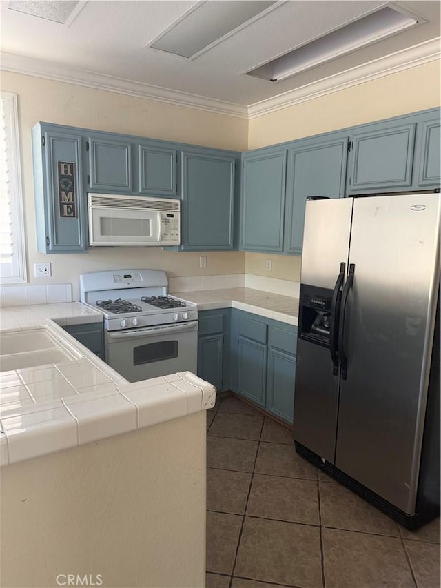 kitchen featuring white appliances, blue cabinetry, and tile counters