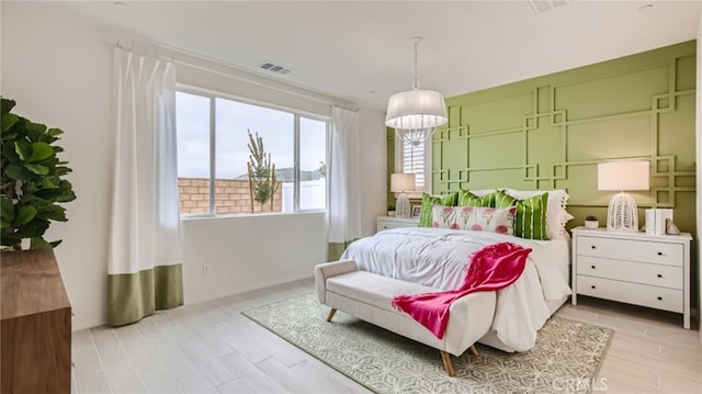 bedroom with visible vents, a notable chandelier, and light wood-style flooring