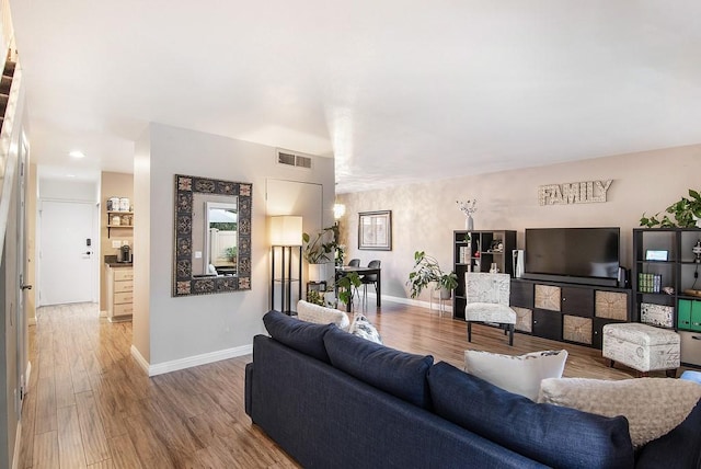 living area featuring visible vents, baseboards, and wood finished floors