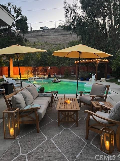 view of swimming pool with a fenced backyard, an outdoor hangout area, a fenced in pool, and a patio