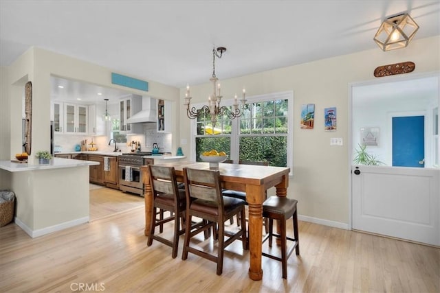 dining room featuring a chandelier, light wood-style flooring, and baseboards