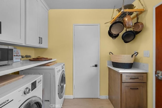 clothes washing area with cabinet space, baseboards, and separate washer and dryer