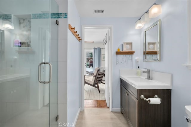 bathroom featuring connected bathroom, wood finished floors, vanity, visible vents, and a shower stall