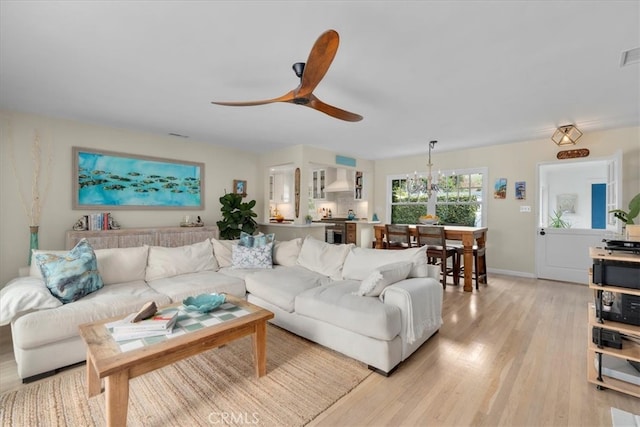 living area with light wood-style flooring, visible vents, baseboards, and ceiling fan with notable chandelier