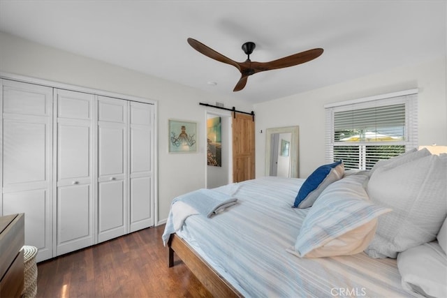 bedroom with dark wood-style floors, a closet, ceiling fan, and a barn door