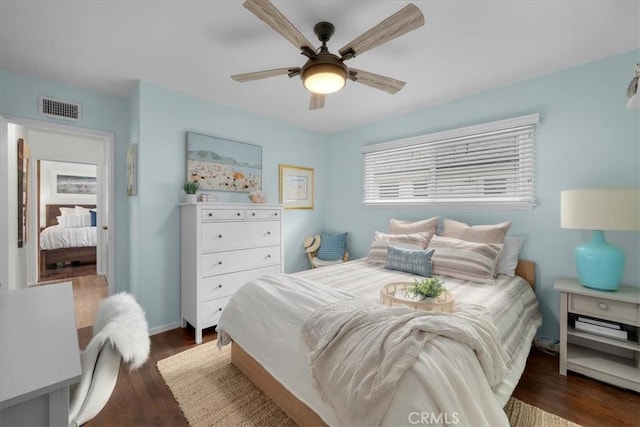 bedroom with ceiling fan, wood finished floors, visible vents, and baseboards