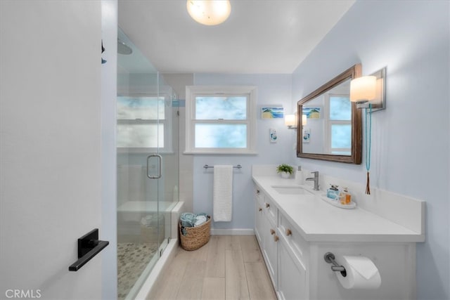 full bathroom with baseboards, vanity, a shower stall, and wood finished floors