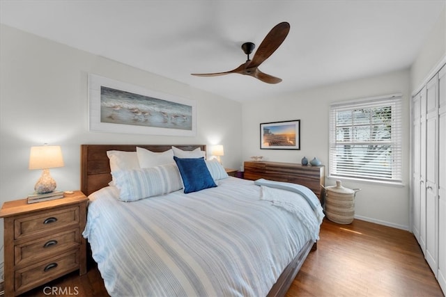 bedroom featuring a ceiling fan, a closet, baseboards, and wood finished floors