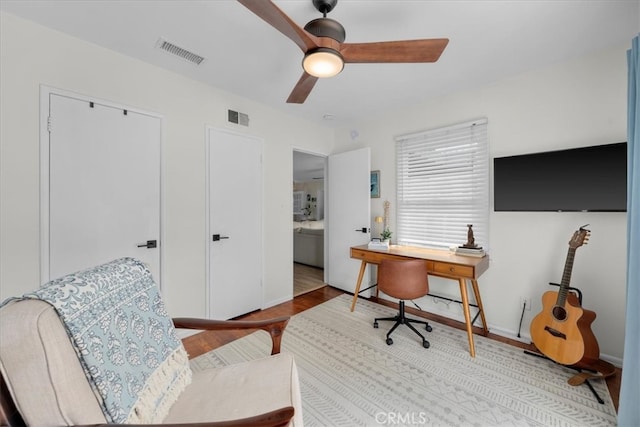 office area featuring a ceiling fan, visible vents, and wood finished floors