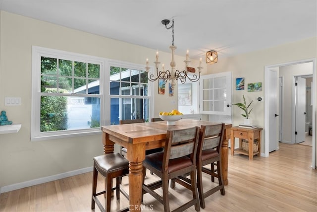 dining space featuring light wood-style floors, baseboards, and a chandelier