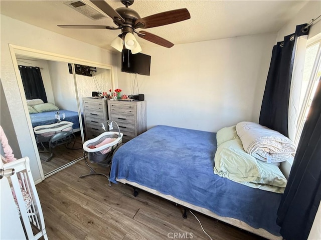 bedroom featuring ceiling fan, visible vents, and wood finished floors