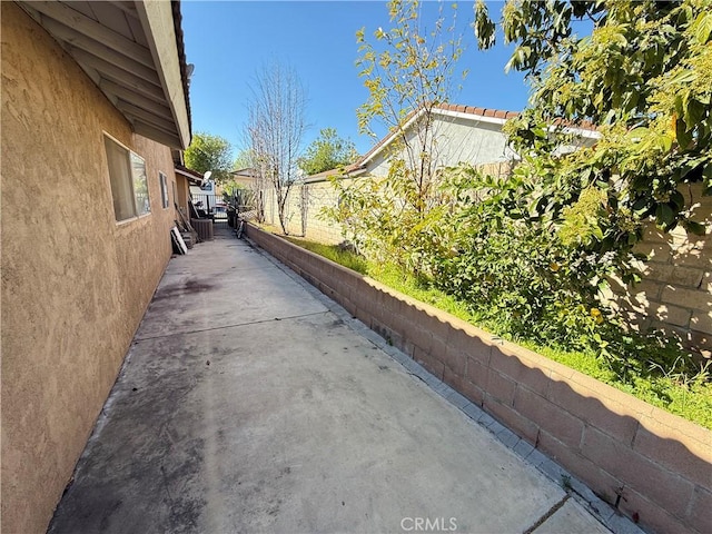 view of side of home with a patio, a tile roof, a fenced backyard, and stucco siding