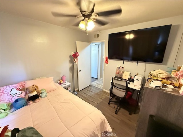 bedroom with baseboards, ceiling fan, visible vents, and wood finished floors