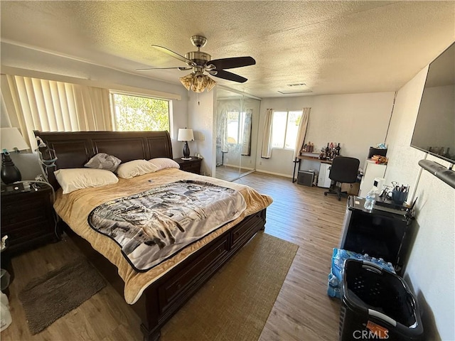 bedroom with ceiling fan, a textured ceiling, baseboards, and wood finished floors