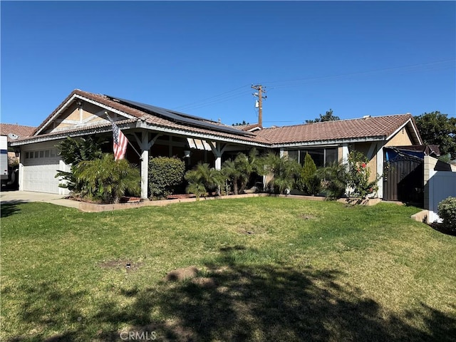 view of front facade with a front yard, a tiled roof, an attached garage, and solar panels