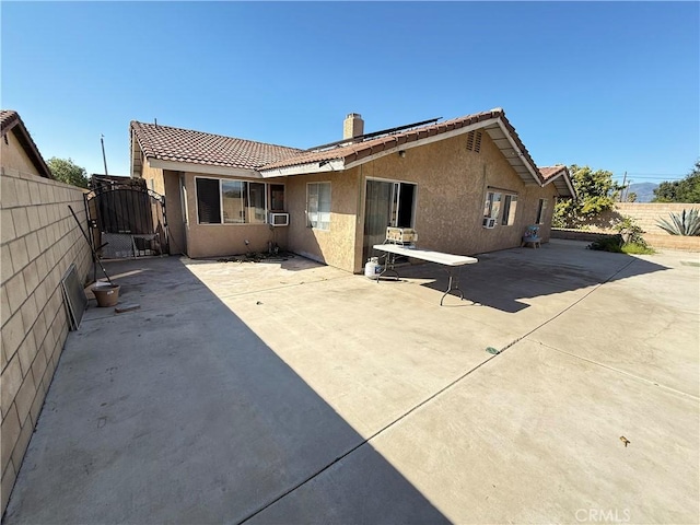 rear view of property with a patio, fence, a gate, stucco siding, and a chimney