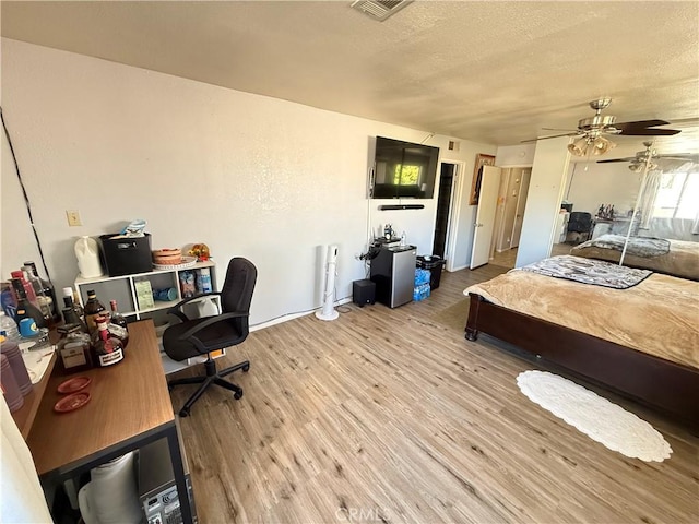 interior space featuring a textured ceiling, ceiling fan, light wood-type flooring, and visible vents