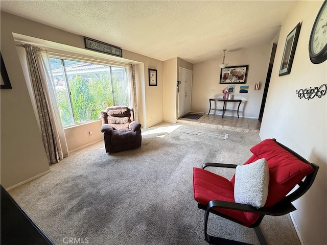 sitting room with lofted ceiling, baseboards, a textured ceiling, and light colored carpet