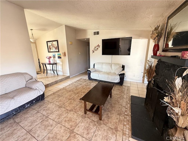 living room with lofted ceiling, a textured ceiling, tile patterned flooring, and visible vents