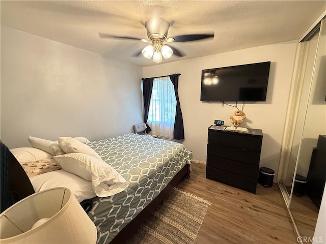 bedroom featuring a ceiling fan, a closet, a textured ceiling, and wood finished floors