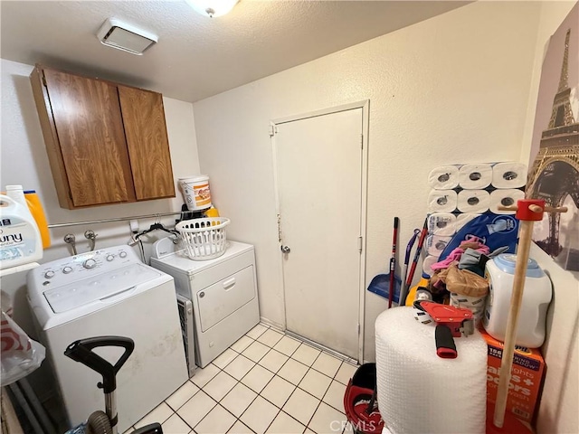 washroom featuring cabinet space, light tile patterned floors, a textured ceiling, and independent washer and dryer