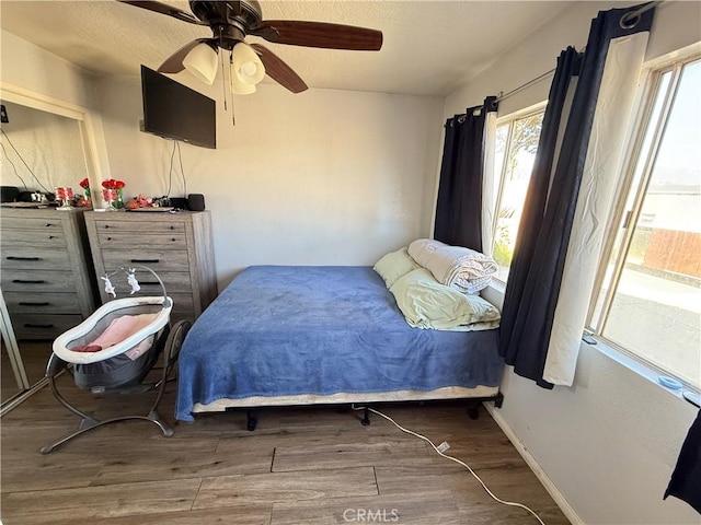 bedroom with ceiling fan, wood finished floors, and baseboards