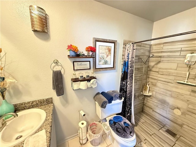 bathroom with tiled shower, vanity, and toilet