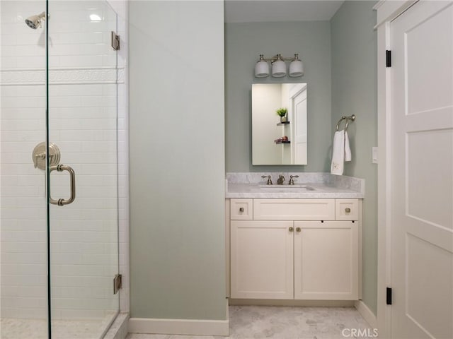 full bath featuring a stall shower, vanity, and baseboards