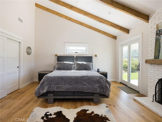 bedroom with visible vents, light wood-style flooring, access to outside, a fireplace, and beam ceiling