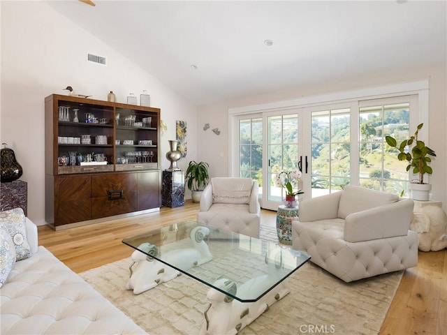 living area with lofted ceiling, visible vents, and wood finished floors