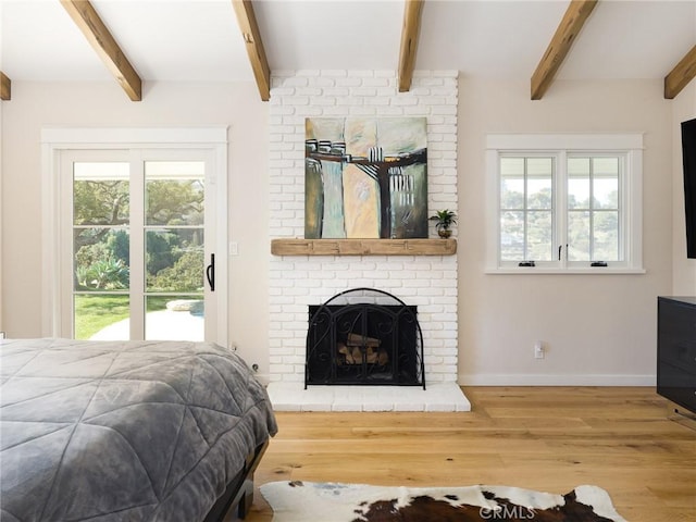 bedroom with multiple windows, a fireplace, baseboards, and wood finished floors