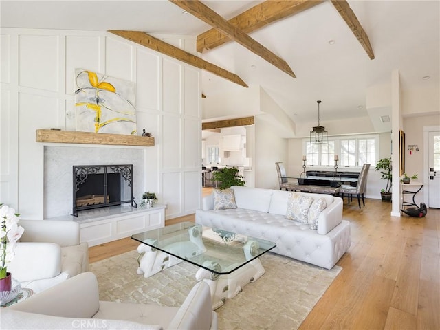 living area with a decorative wall, beamed ceiling, a fireplace, and light wood-style floors