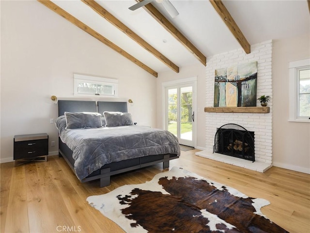 bedroom with a brick fireplace, access to exterior, multiple windows, and beamed ceiling