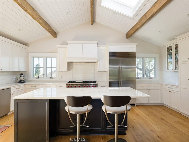 kitchen with glass insert cabinets, a kitchen island, white cabinetry, and stainless steel appliances