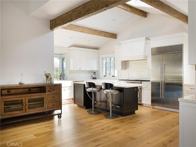 kitchen with light countertops, a breakfast bar, high end appliances, and white cabinets