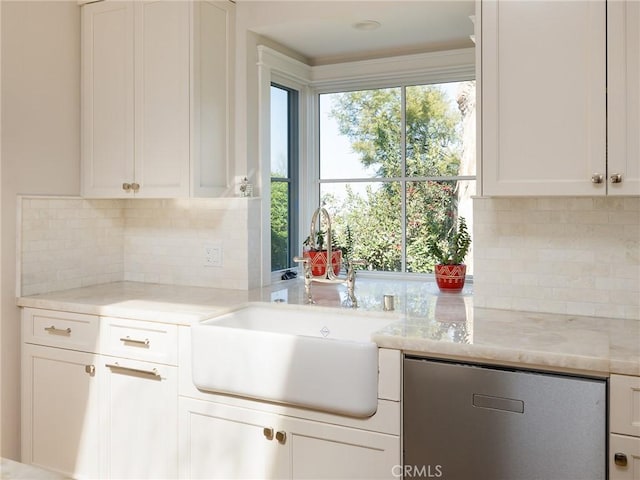 kitchen with light stone counters, decorative backsplash, stainless steel dishwasher, white cabinetry, and a sink