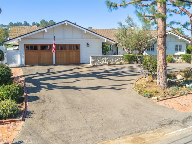 ranch-style home featuring a garage, driveway, board and batten siding, and fence