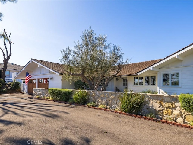 ranch-style house with board and batten siding, driveway, an attached garage, and fence