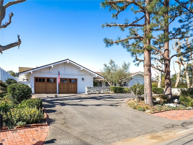 view of front of house with driveway, an attached garage, fence, and board and batten siding