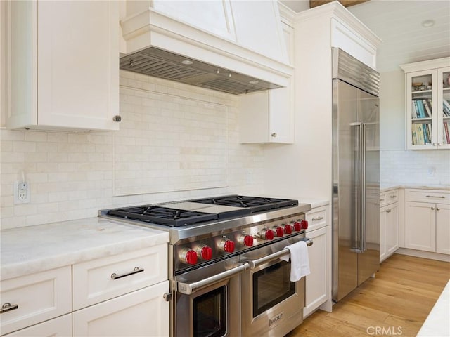 kitchen with glass insert cabinets, custom exhaust hood, high quality appliances, and white cabinets