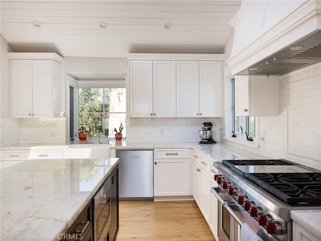 kitchen with a sink, stainless steel appliances, custom exhaust hood, and white cabinetry