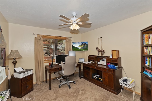 office featuring ceiling fan, baseboards, a textured ceiling, and light colored carpet