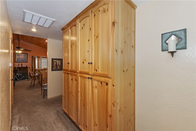 corridor featuring vaulted ceiling, dark carpet, and visible vents