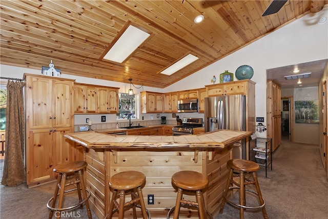 kitchen with a breakfast bar, tile counters, visible vents, appliances with stainless steel finishes, and a sink