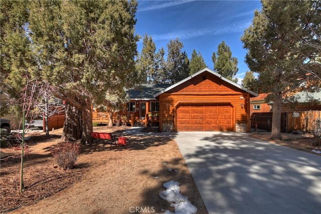 view of front of house with concrete driveway, stone siding, an attached garage, and fence