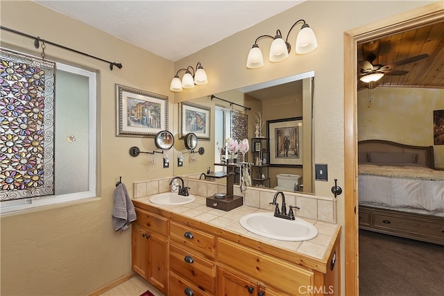 full bathroom featuring toilet, double vanity, a sink, and ensuite bathroom