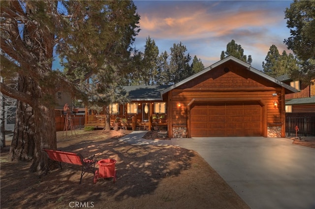 chalet / cabin with stone siding, driveway, and an attached garage