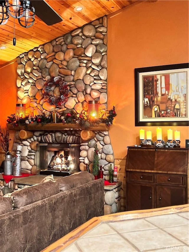 living area featuring vaulted ceiling, a fireplace, wood ceiling, and a ceiling fan